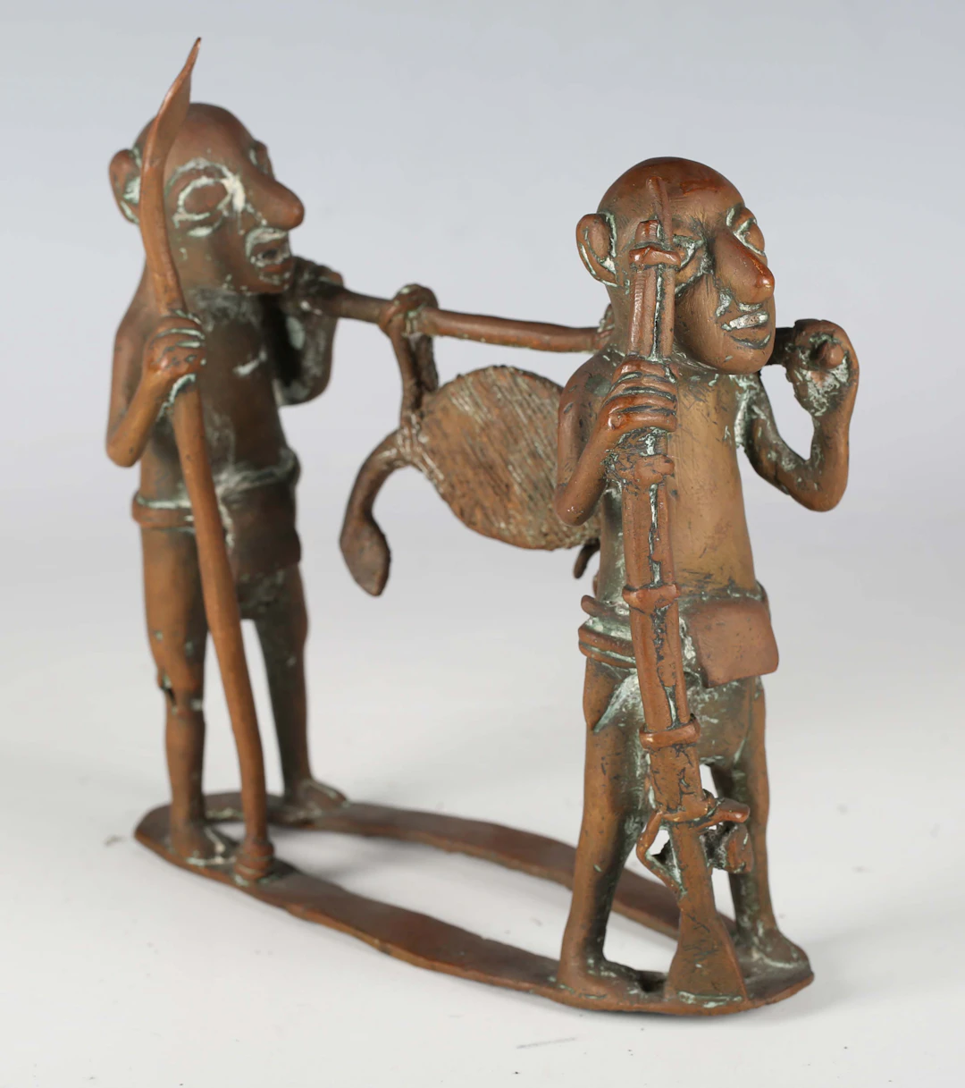 An African cast copper alloy figure group of two figures carrying