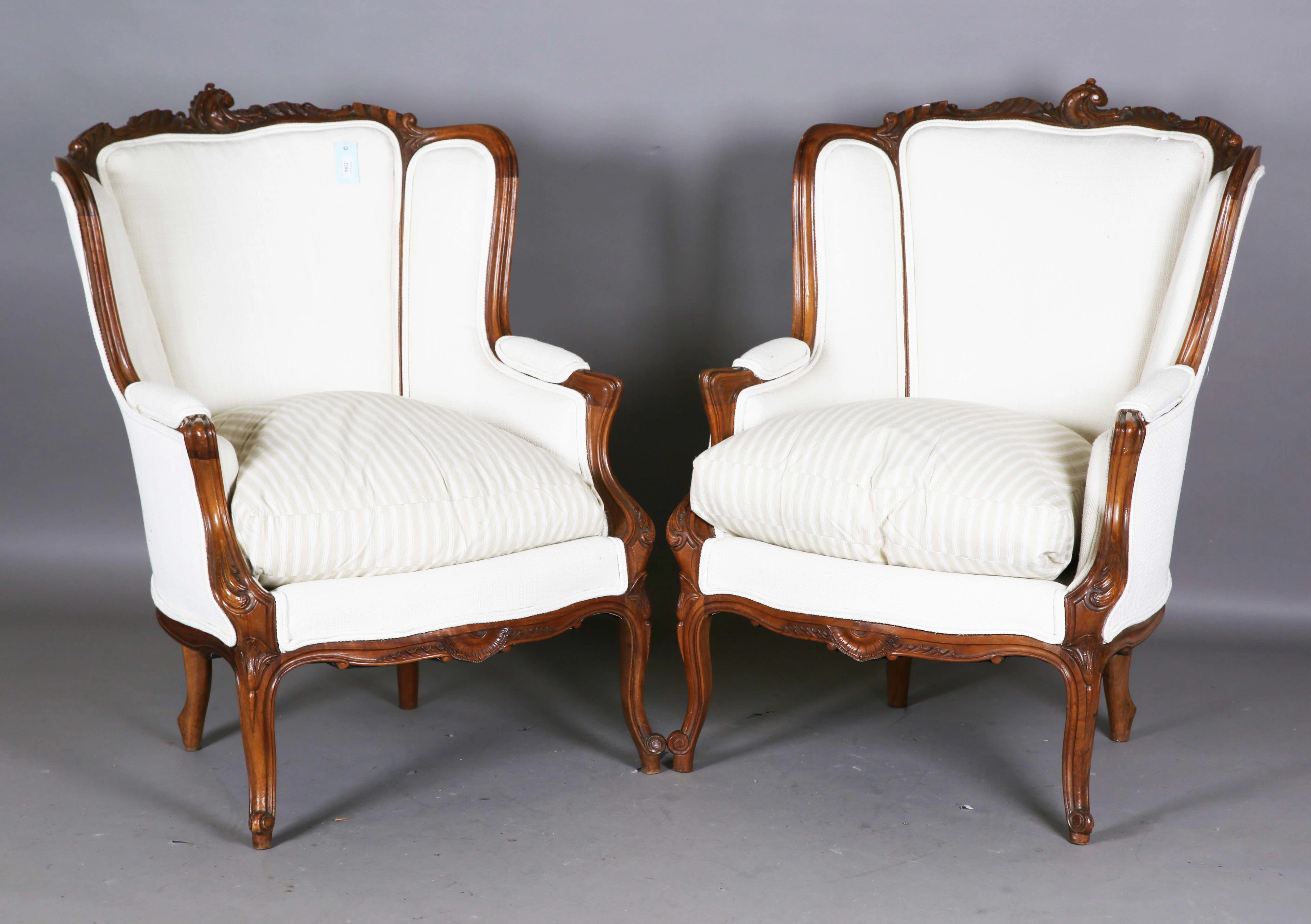 A pair of early 20th century French walnut showframe armchairs with