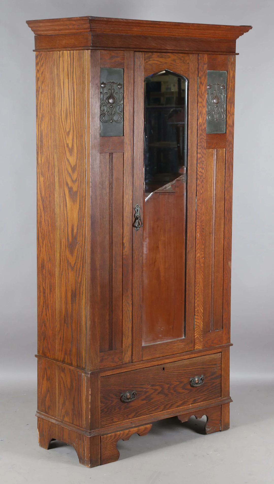 An Edwardian Arts and Crafts oak wardrobe, inset with two pressed