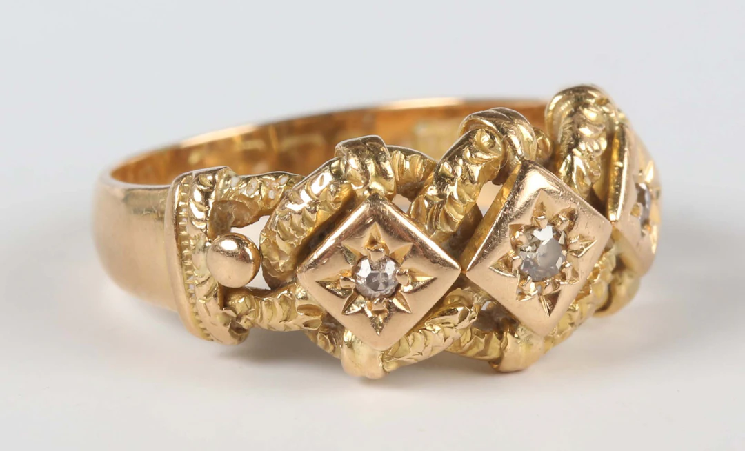 An 18ct gold and diamond three stone ring in an interwoven and beaded