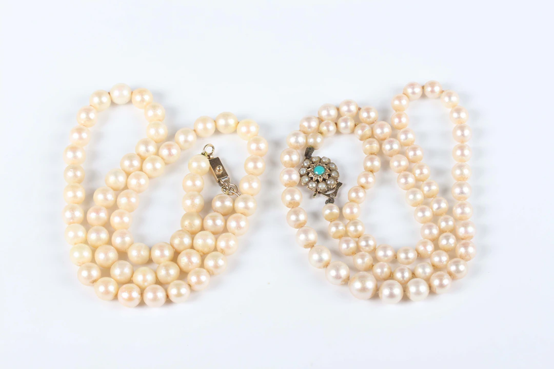A single row necklace of graduated cultured pearls on a gold, turquoise