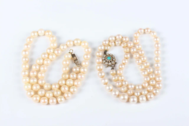 A single row necklace of graduated cultured pearls on a gold, turquoise