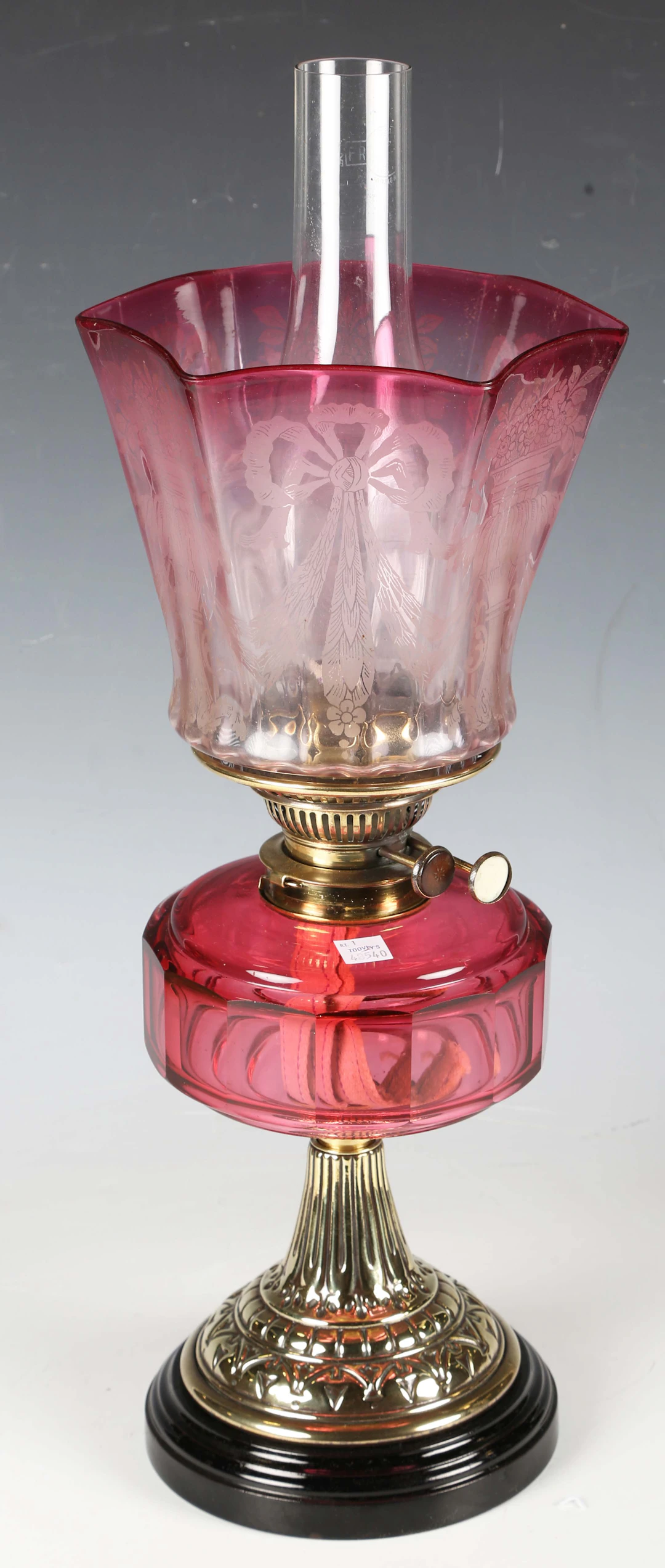 A Victorian brass and cranberry glass table oil lamp with an etched