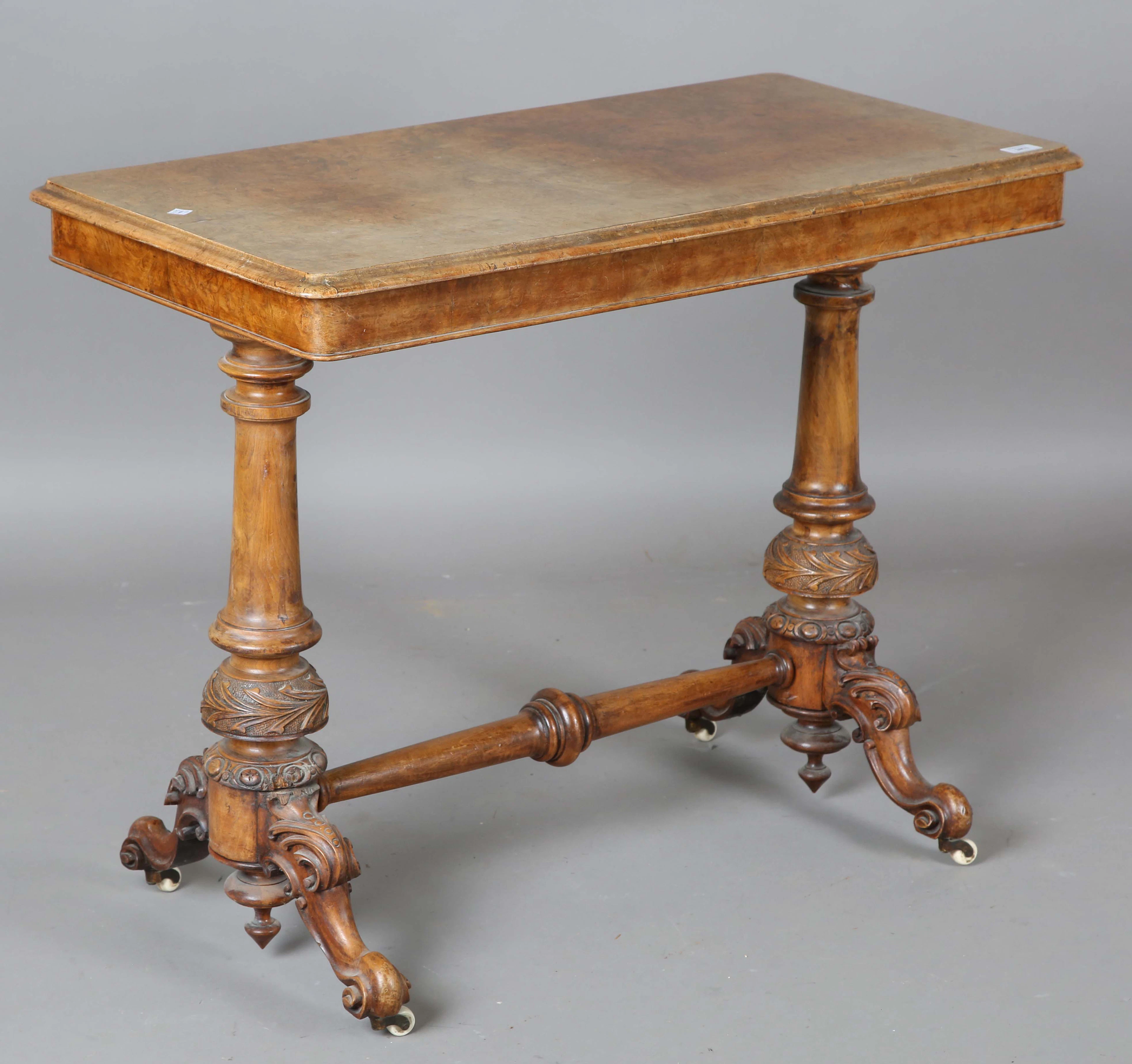 A mid-Victorian burr walnut stretcher table with carved foliate supports