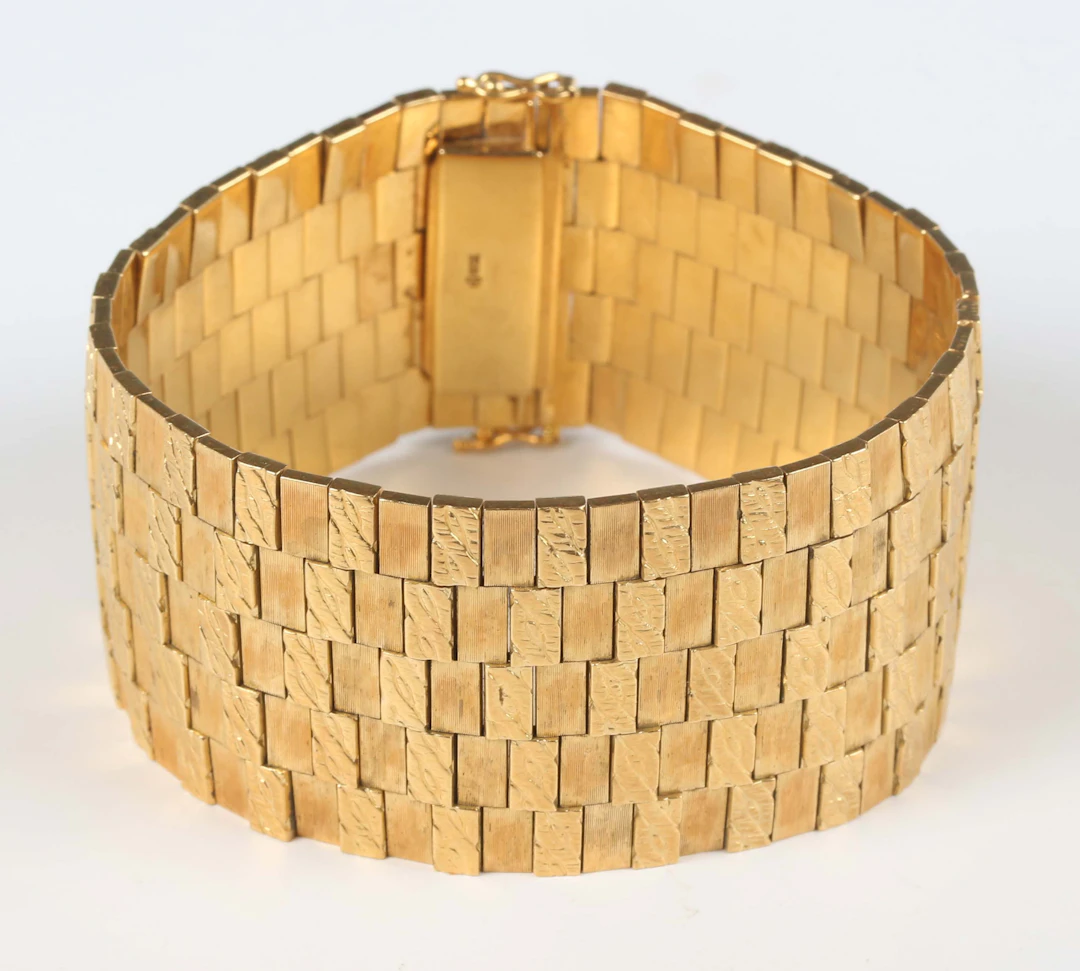 A gold wide textured link bracelet on a snap clasp, detailed ‘750’