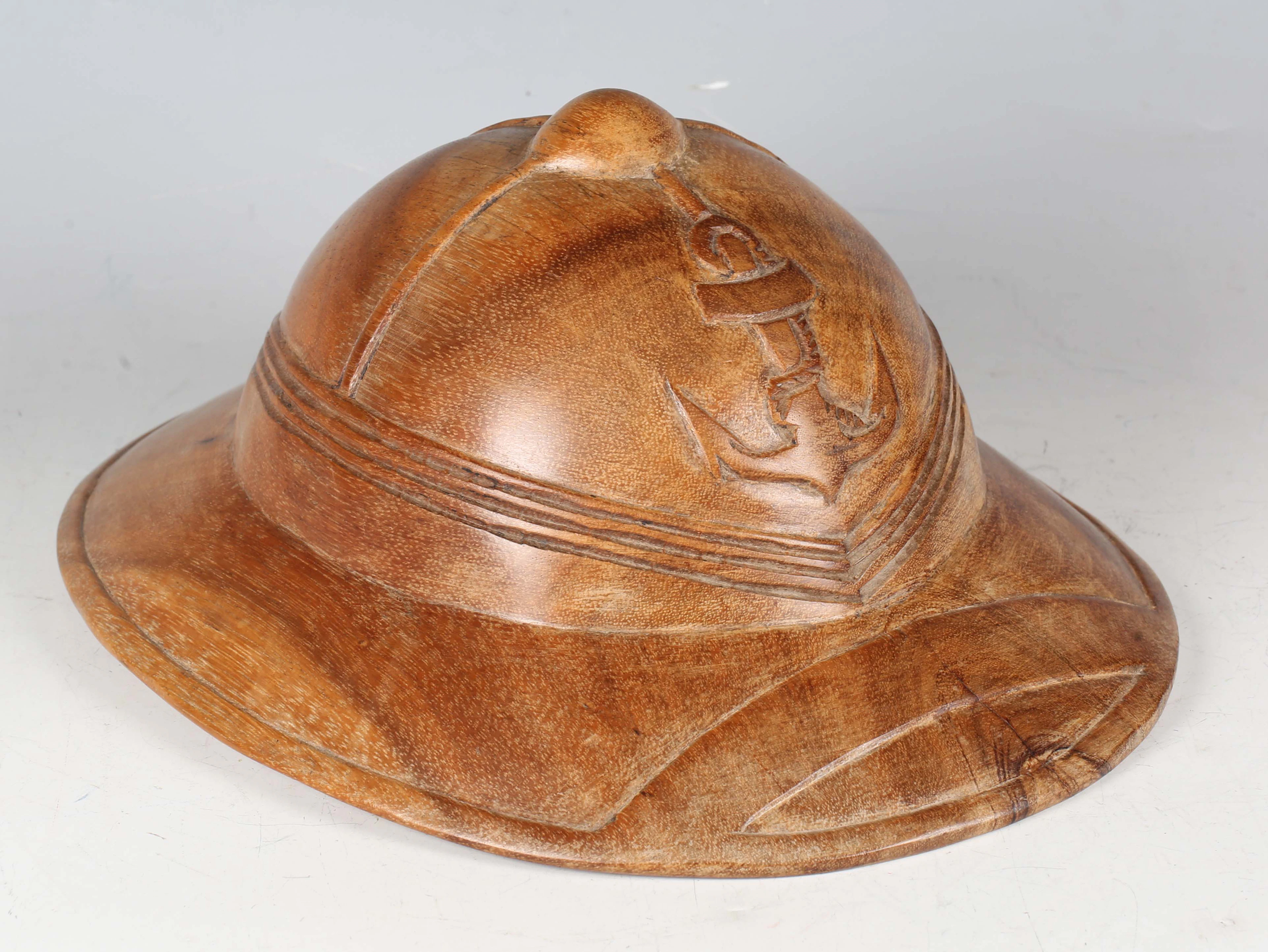A penal colony carved wood helmet for French forces, probably carved