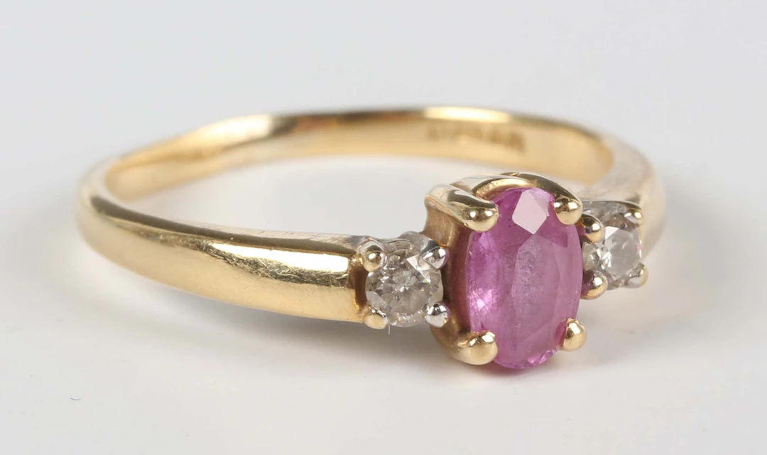 An 18ct gold ring, claw set with an oval cut pink sapphire between