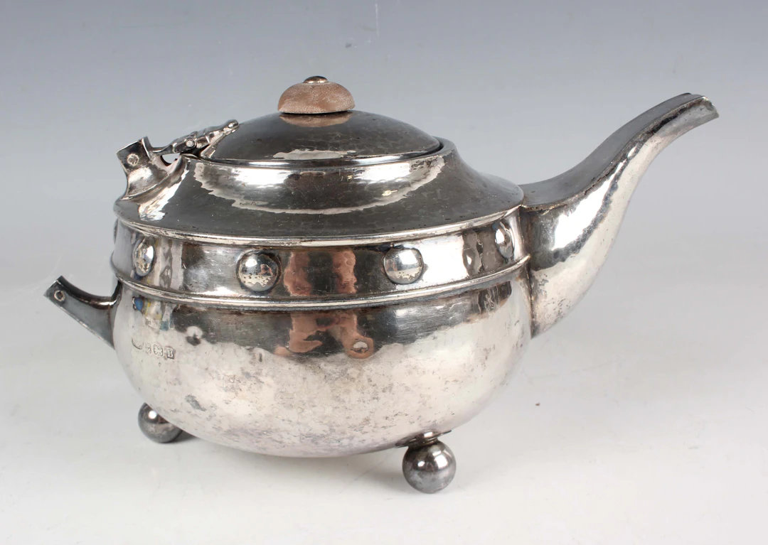 An Arts and Crafts style silver circular teapot, decorated with a