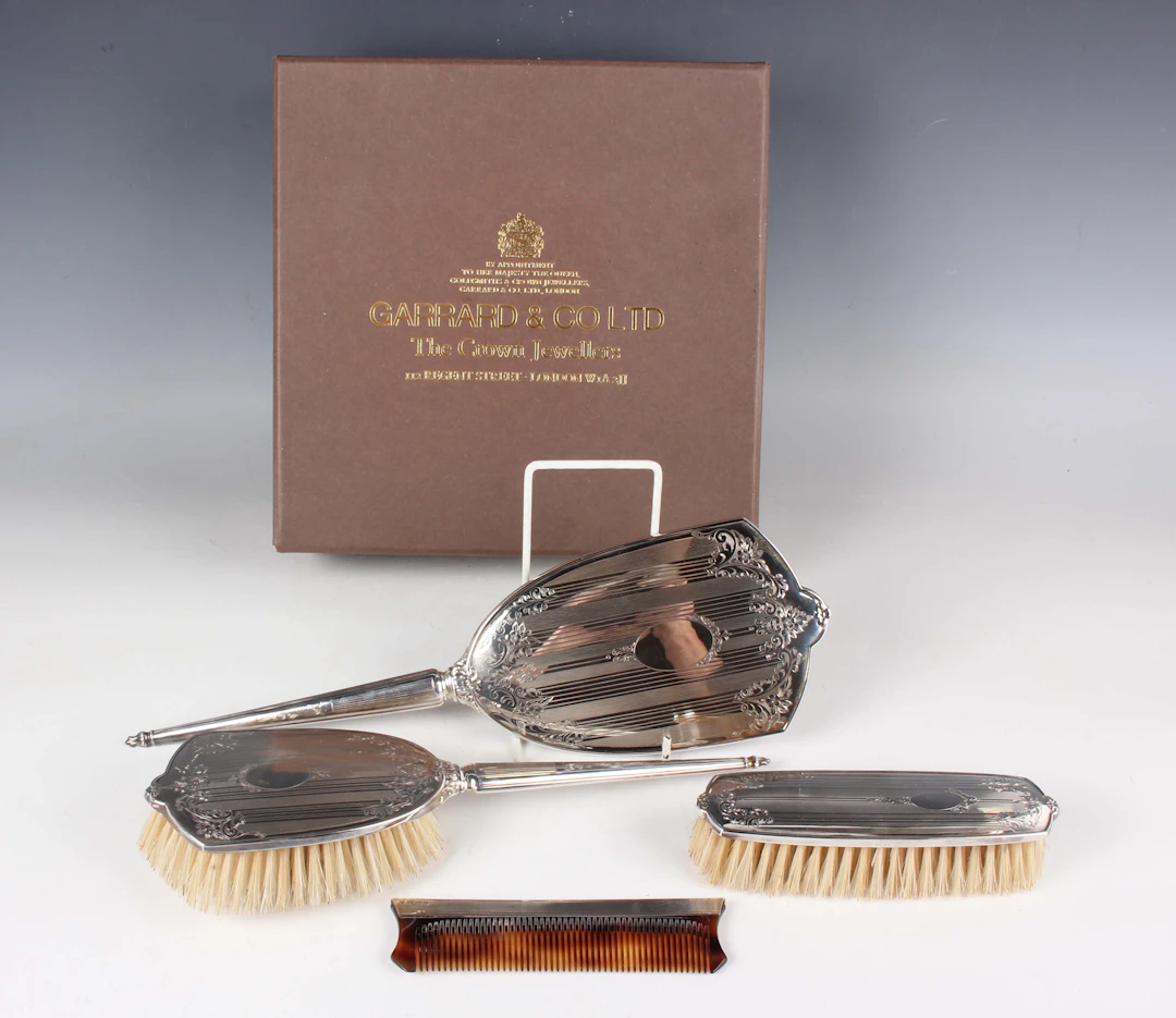 An Elizabeth II silver four-piece dressing table set, engraved with