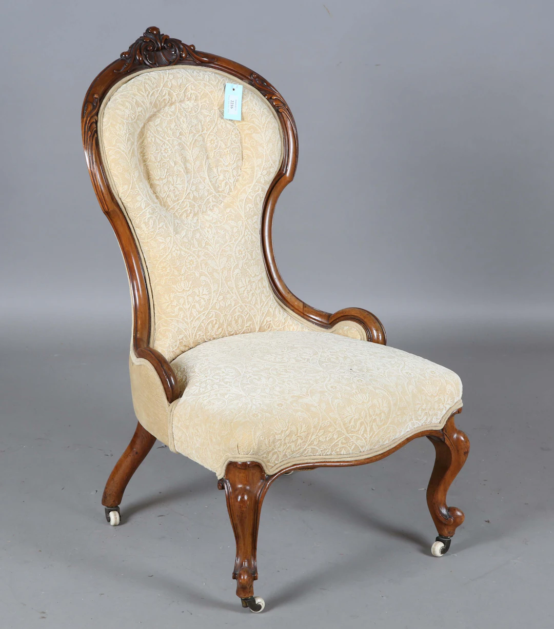A mid-Victorian walnut showframe salon chair with a carved foliate
