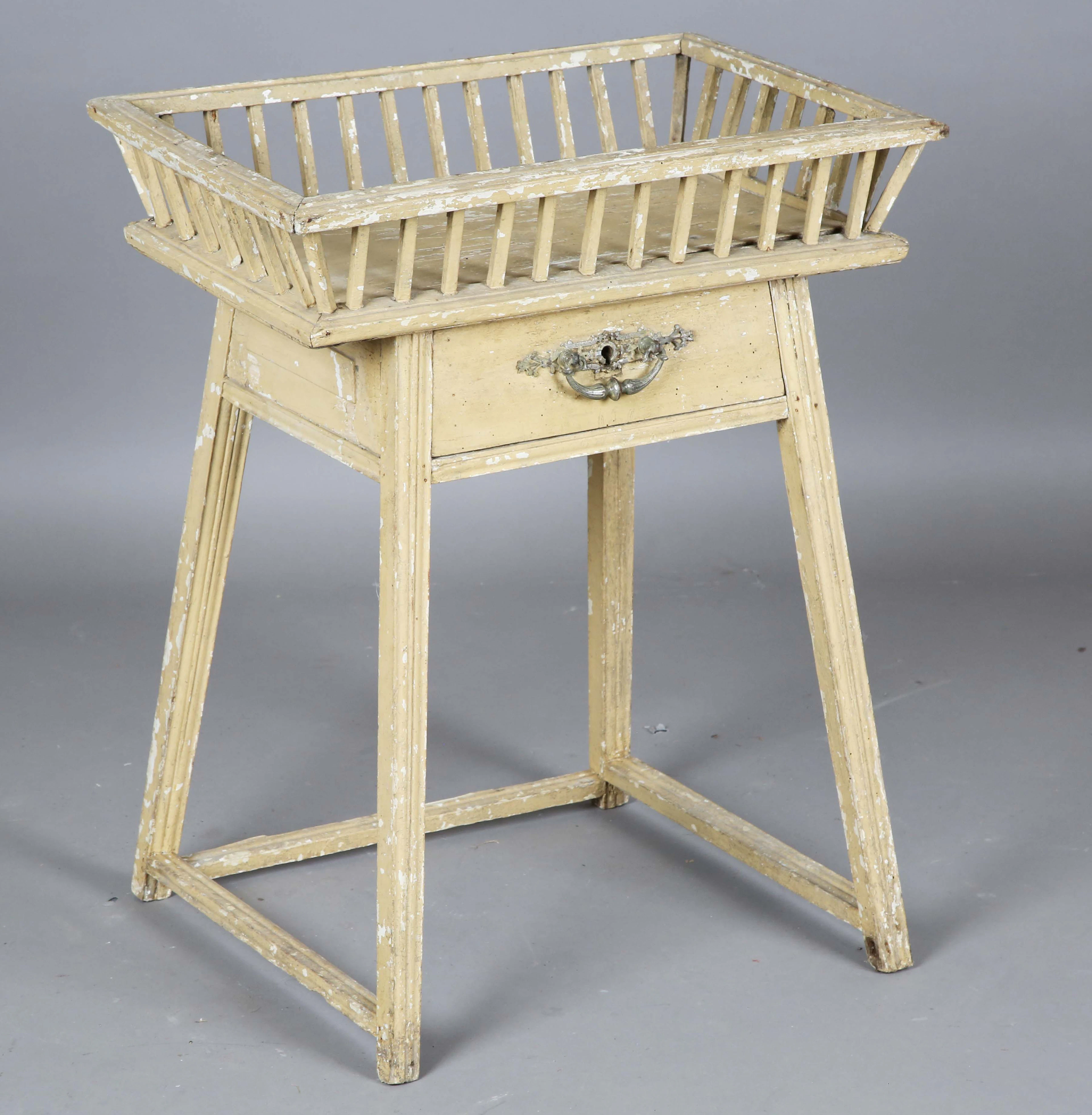 An early 20th century cream painted work table with a raised gallery