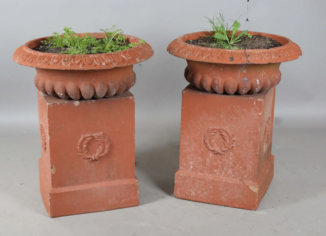A pair of terracotta painted cast stone garden urns of reeded campana