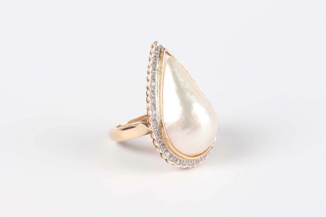 A 9ct gold, mabé pearl and diamond cluster ring, mounted with a pear