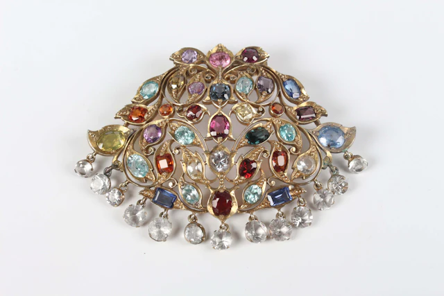 An Asian silver gilt and varicoloured gemstone brooch in a foliate
