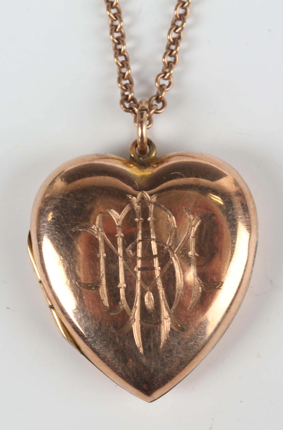 A gold back and front heart shaped pendant locket, the front monogram