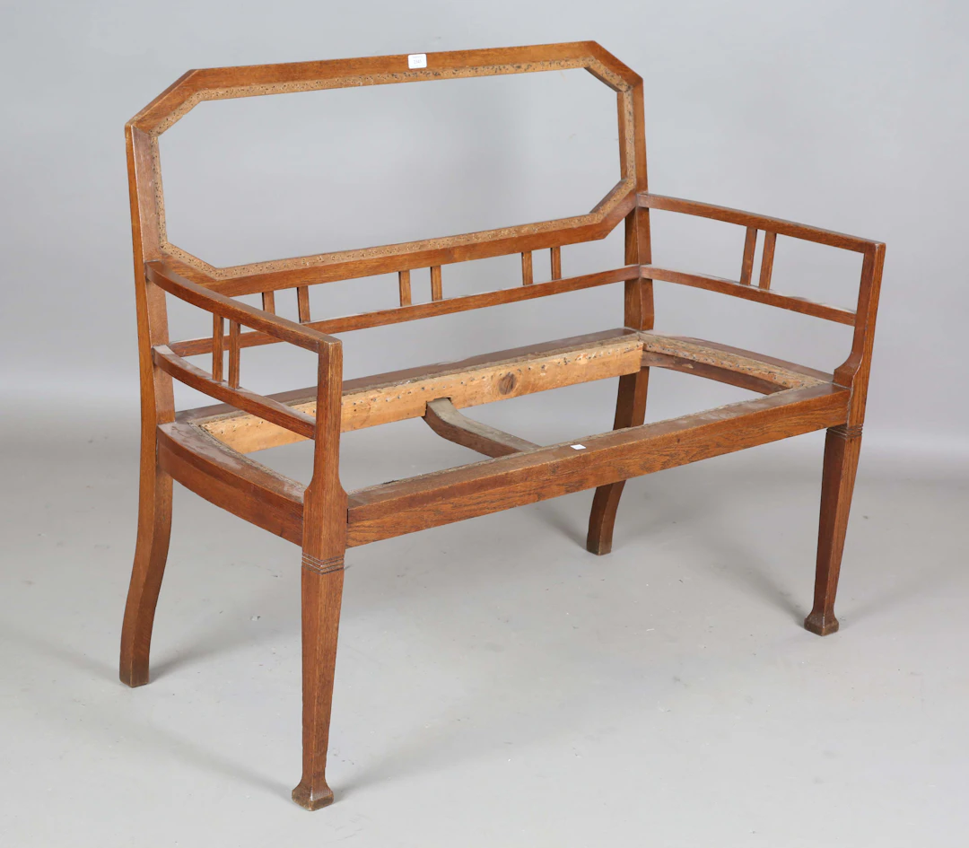 An early 20th century Arts and Crafts oak framed settee frame with