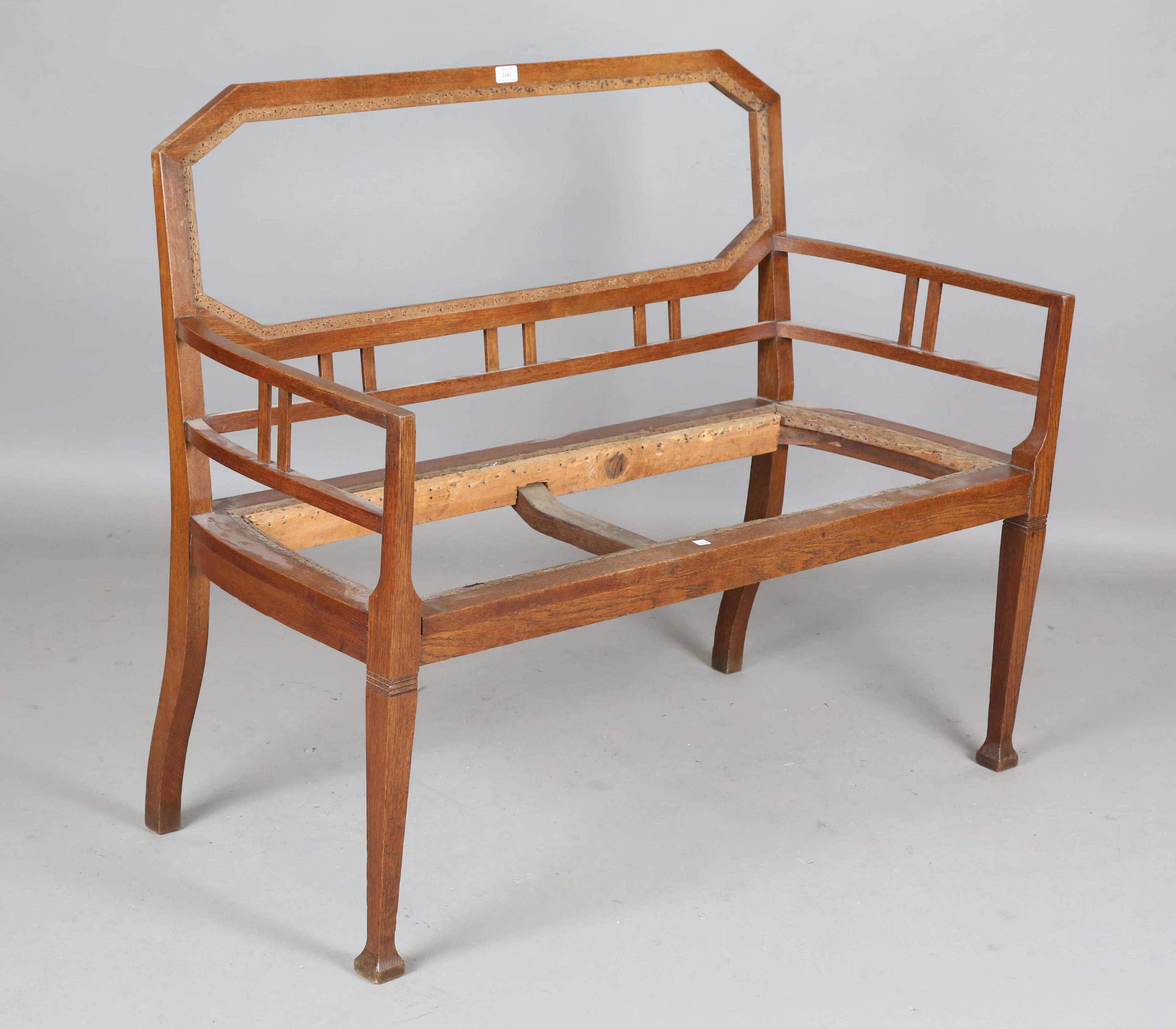 An early 20th century Arts and Crafts oak framed settee frame with