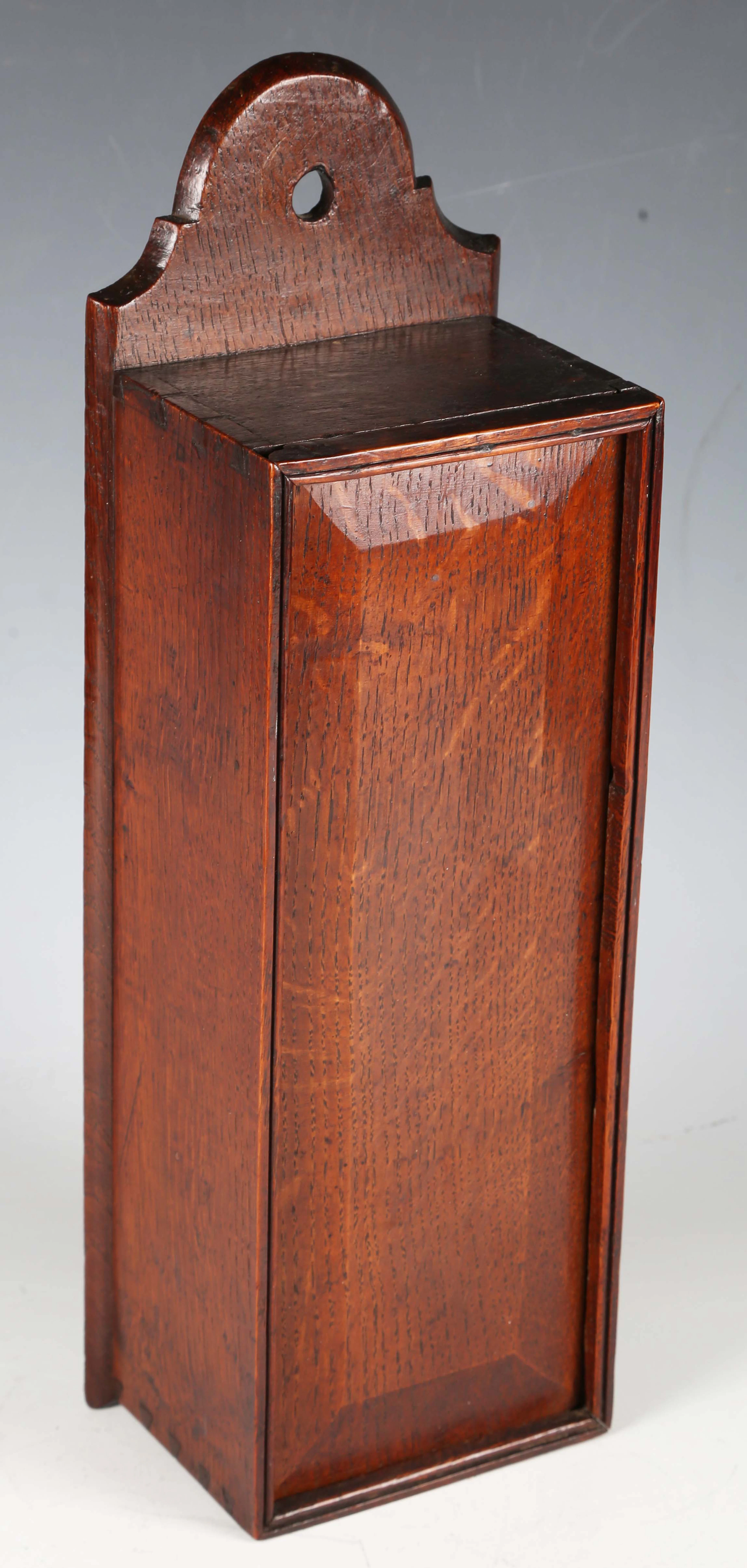 A late George III provincial oak wall mounted candlebox with sliding
