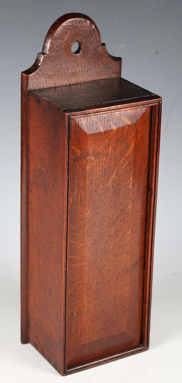 A late George III provincial oak wall mounted candlebox with sliding