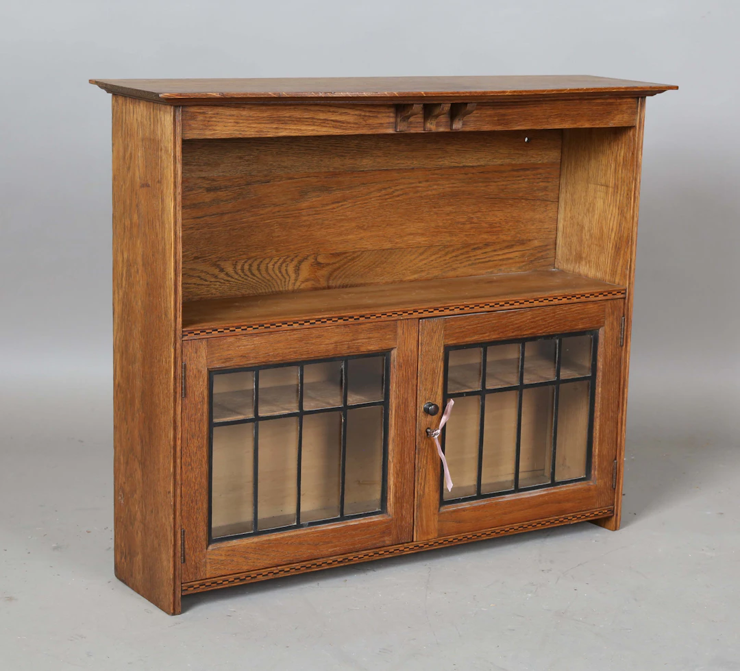 An Edwardian Arts and Crafts oak hanging wall cabinet, in the manner