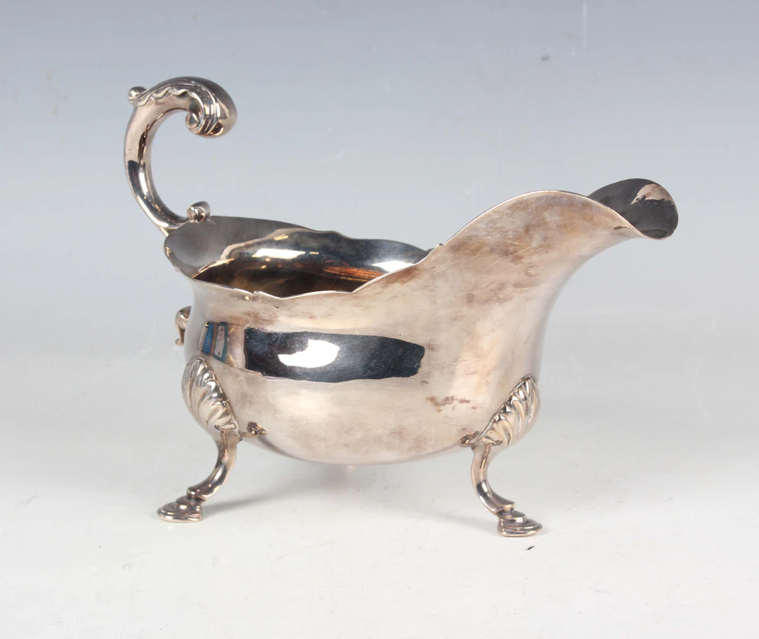 A George III silver sauceboat with shaped rim and foliate capped scroll