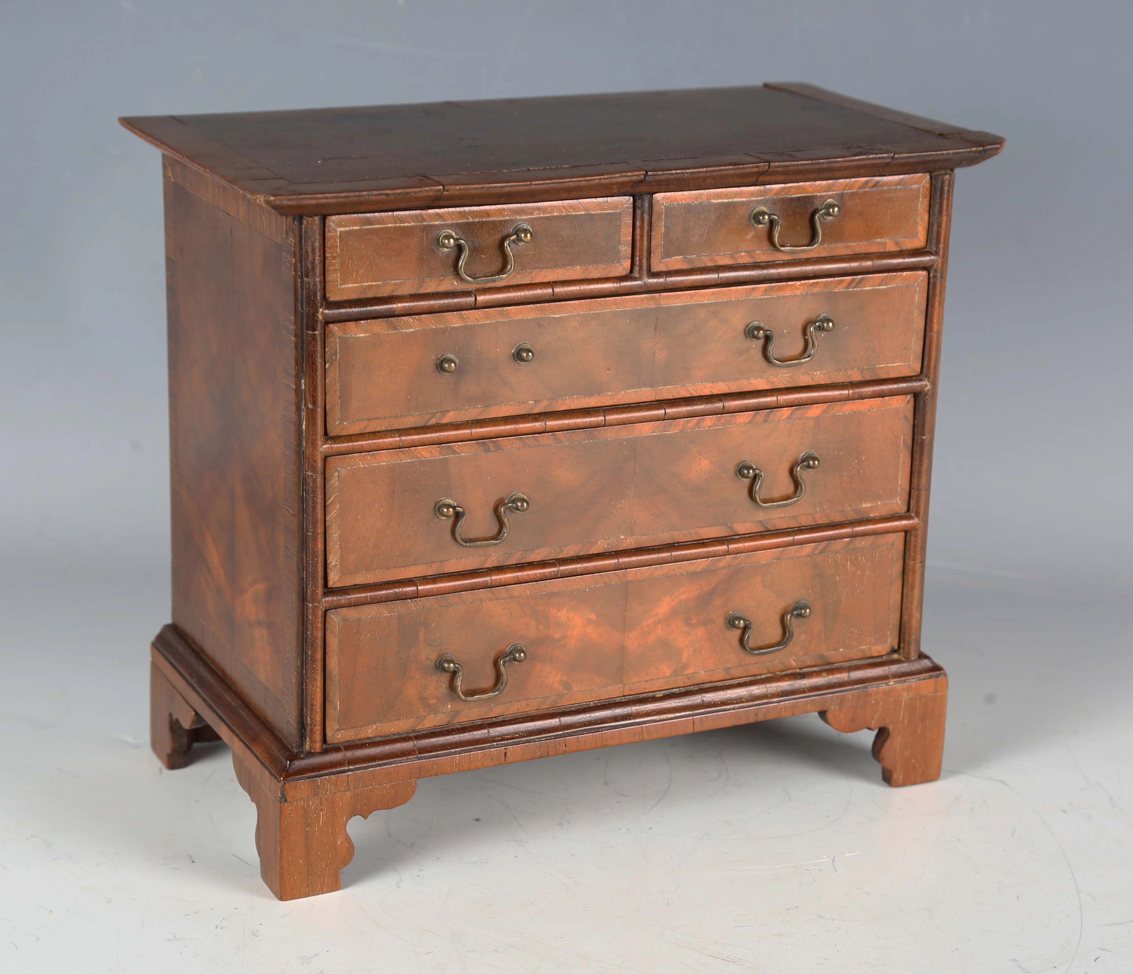 An early 20th century walnut table-top apprentice style chest of drawers