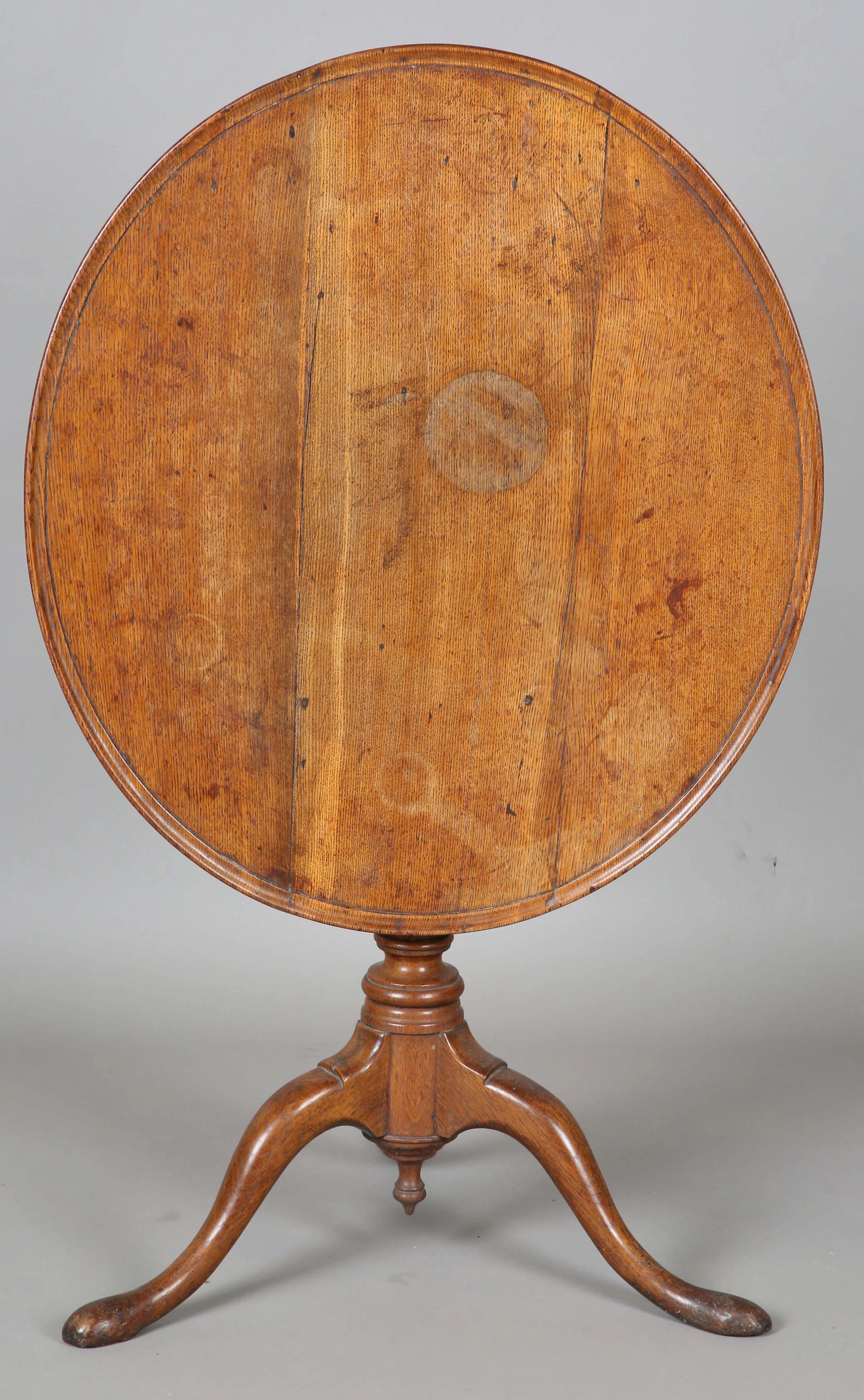 A George III provincial oak oval tip-top supper table, raised on a