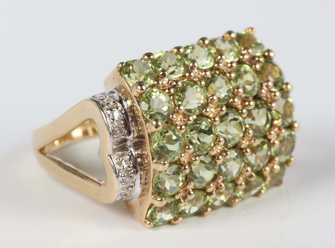 A 9ct gold, peridot and diamond ring in a curved rectangular design