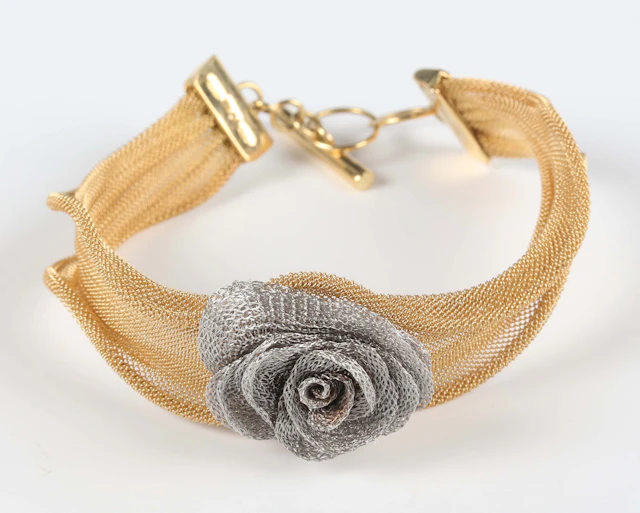 An Italian Fraccari two colour gold bracelet in a ribbon fold woven