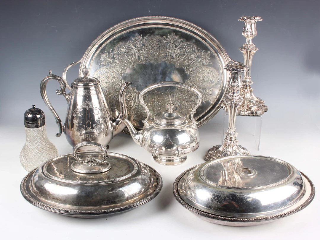 A group of plated items, including a pair of candlesticks, a spirit