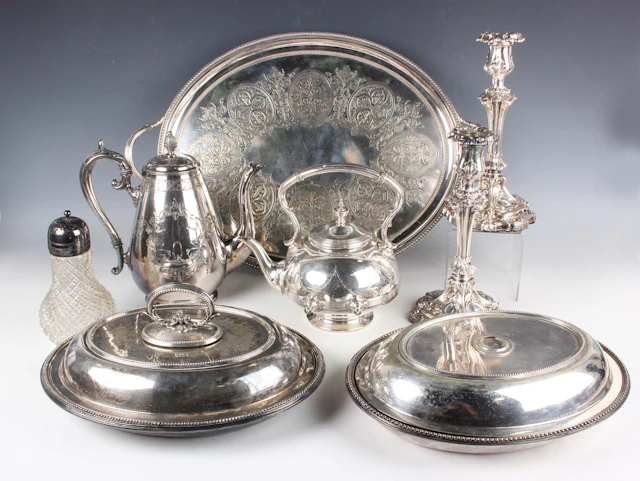 A group of plated items, including a pair of candlesticks, a spirit