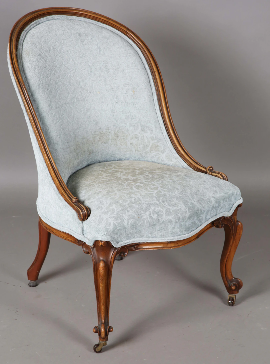 A mid-Victorian walnut showframe salon chair, raised on carved cabriole