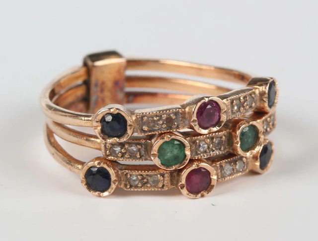 A gold, diamond, emerald, sapphire and ruby ring in a triple shank