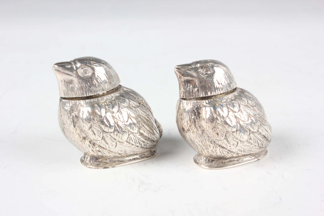 A pair of Edwardian silver novelty pepper casters, each in the form