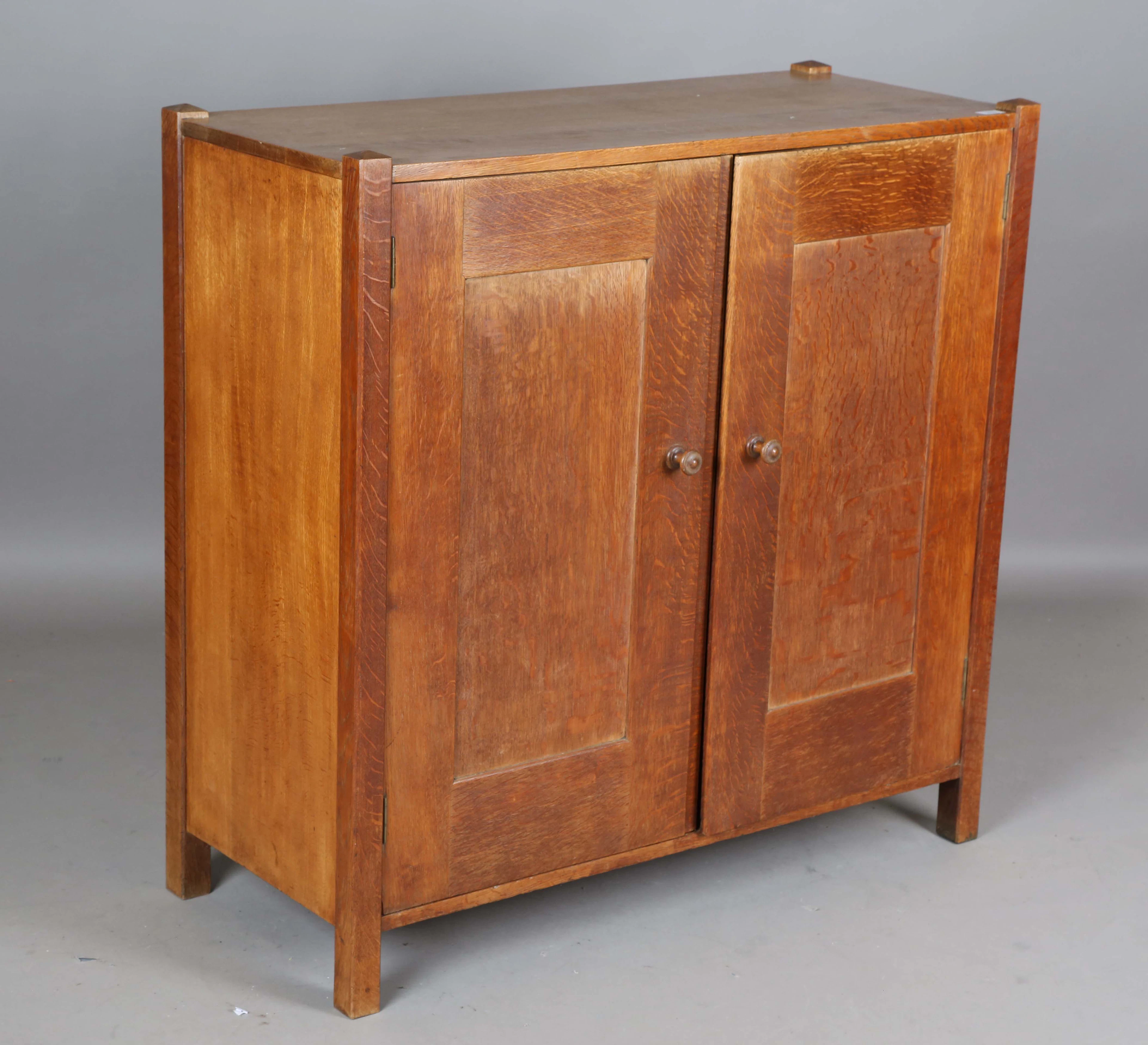 An early 20th century Arts and Crafts oak two-door side cupboard by