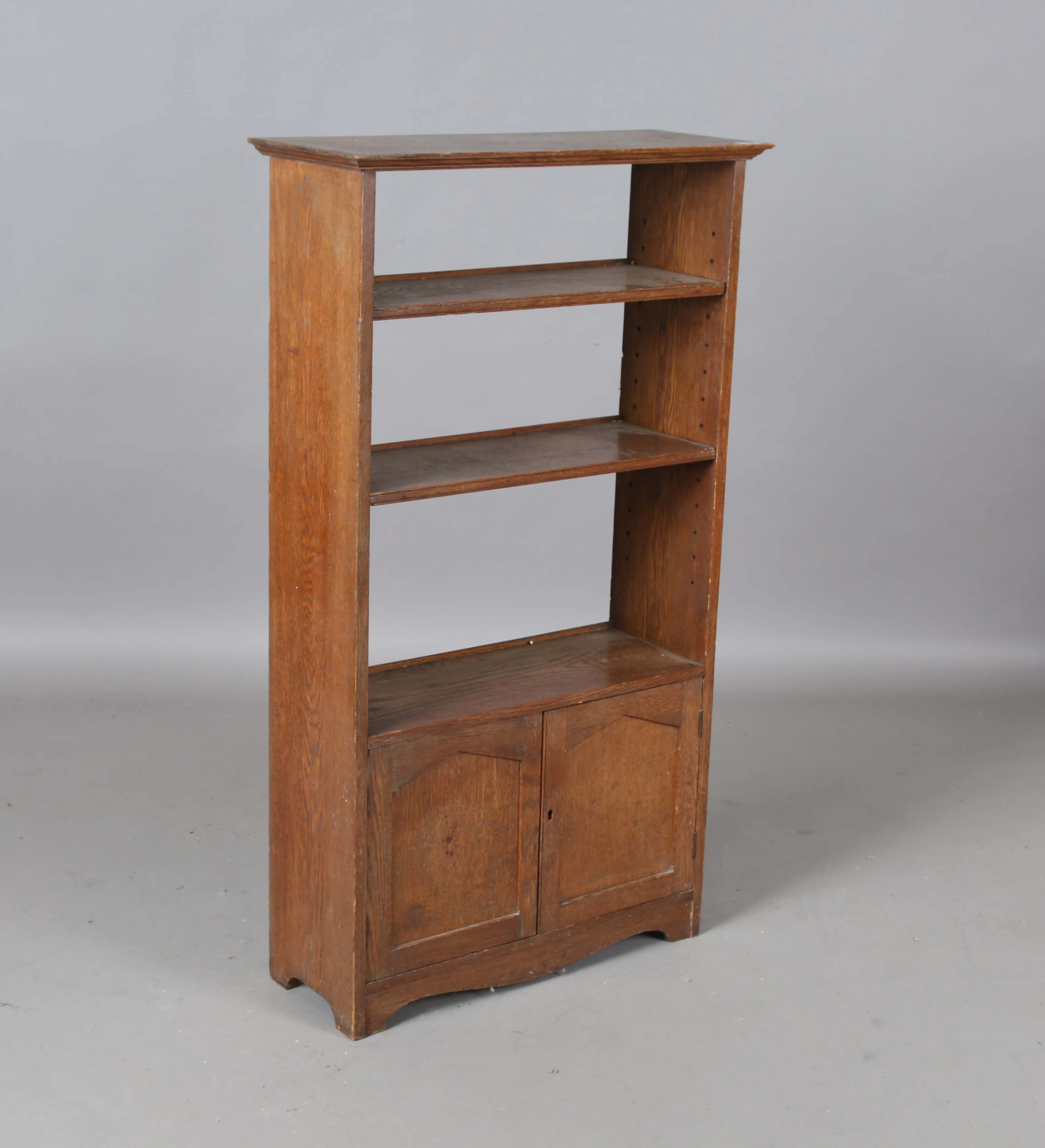 An Edwardian Arts and Crafts oak open bookshelf, fitted with two panelled