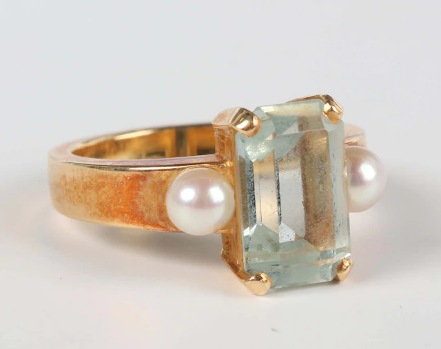 A gold, aquamarine and cultured pearl ring, claw set with a cut cornered