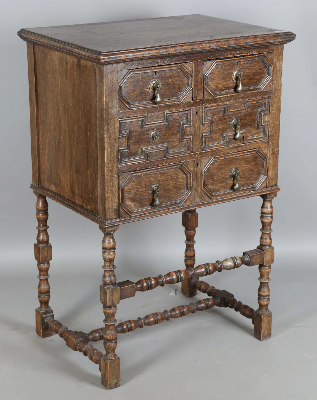 An early 20th century Jacobean Revival oak chest-on-stand, the three