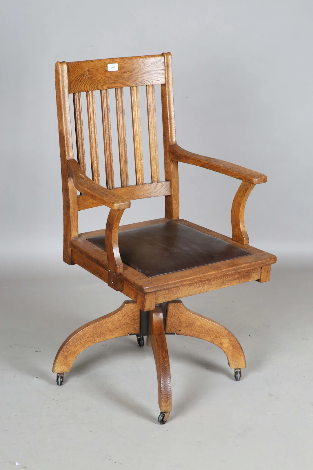 An early 20th century Arts and Crafts style oak framed rail back revolving