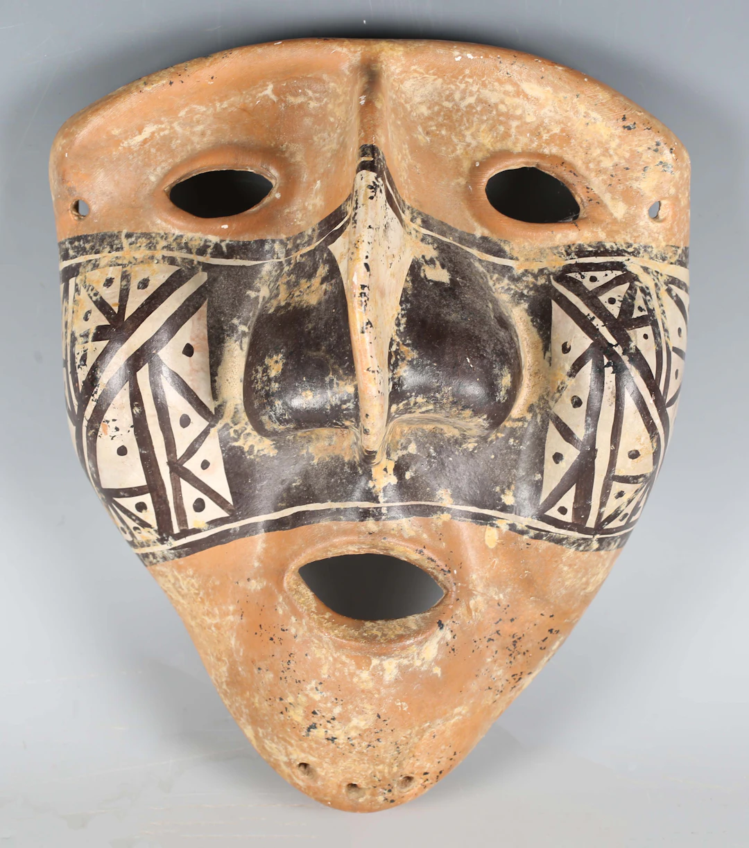 A pre-Columbian style terracotta mask, painted with a band of geometric