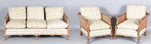 A George V walnut framed three-piece bergère suite, comprising a settee
