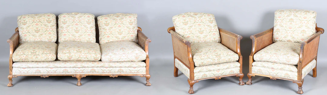 A George V walnut framed three-piece bergère suite, comprising a settee