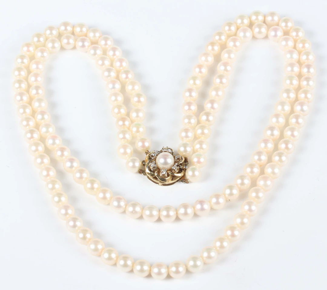 A graduated two row necklace of cultured pearls on a gold, diamond