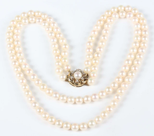 A graduated two row necklace of cultured pearls on a gold, diamond