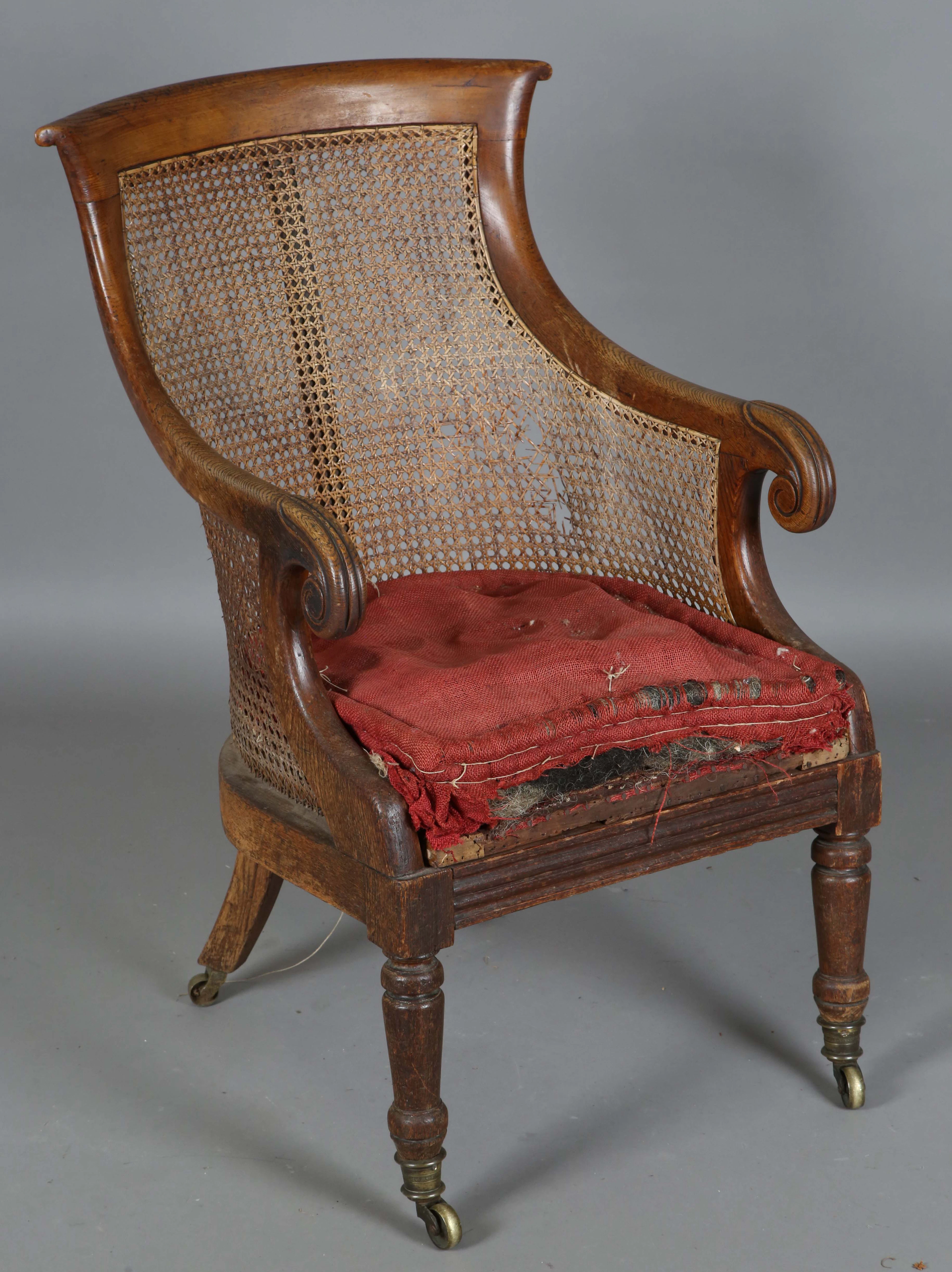 A Regency oak framed bergère library armchair, the shaped back with