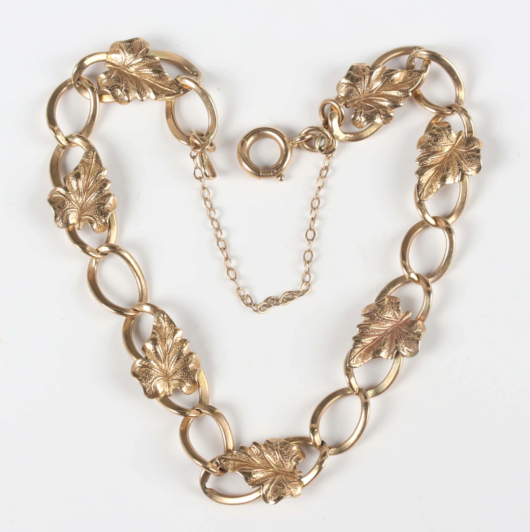 A 9ct gold curblink bracelet, applied with leaf motifs at intervals