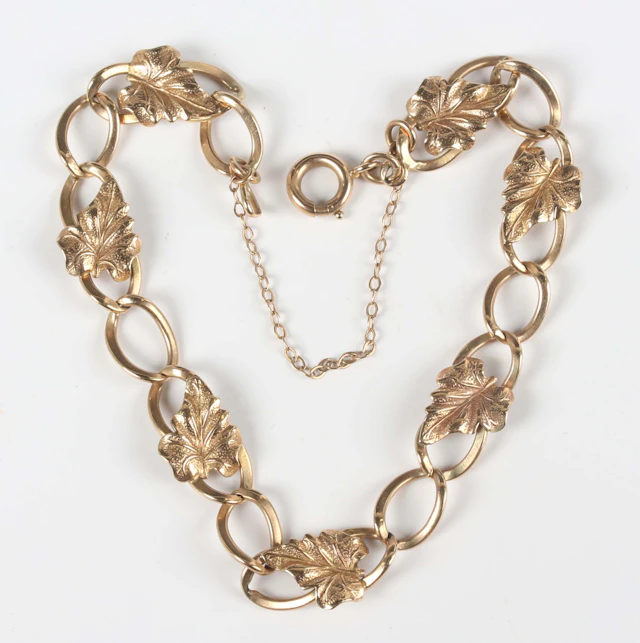 A 9ct gold curblink bracelet, applied with leaf motifs at intervals