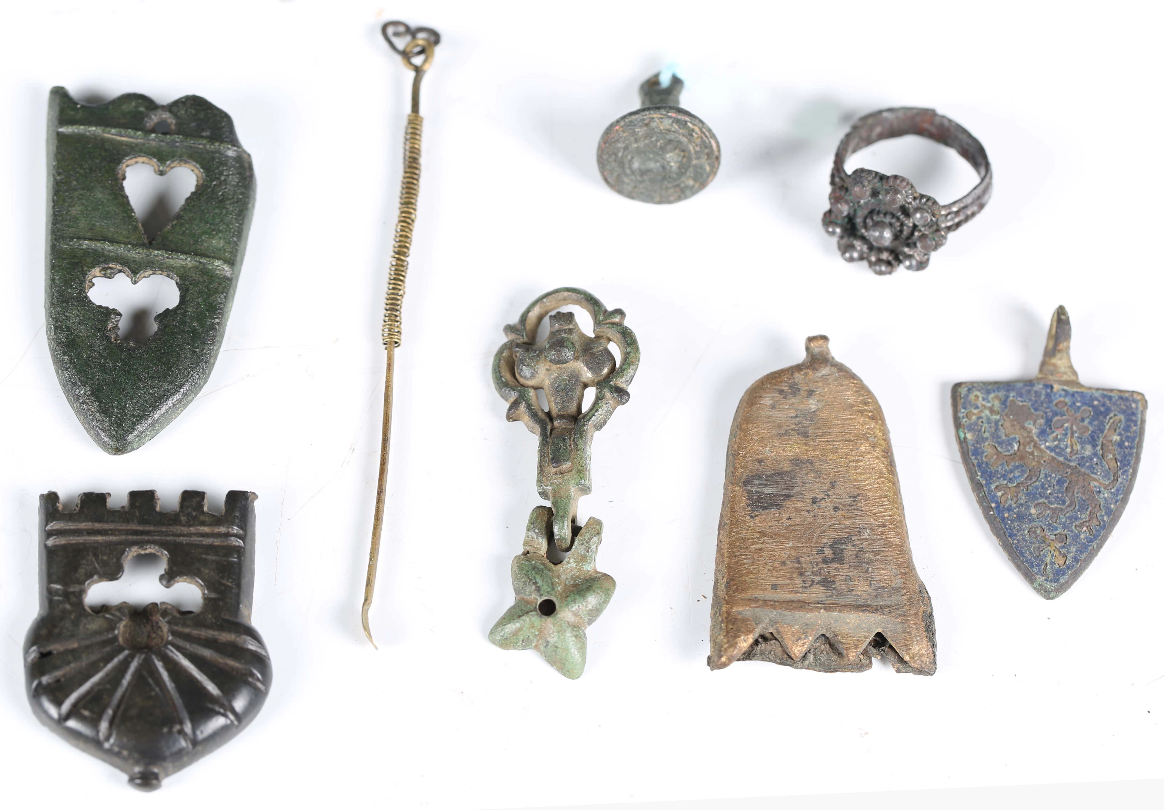 A group of medieval artifacts, including sword chapes, a bronze pendant