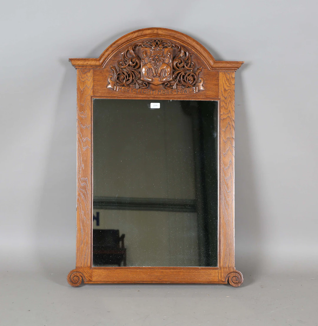 An early 20th century Arts and Crafts oak framed mirror, the arched