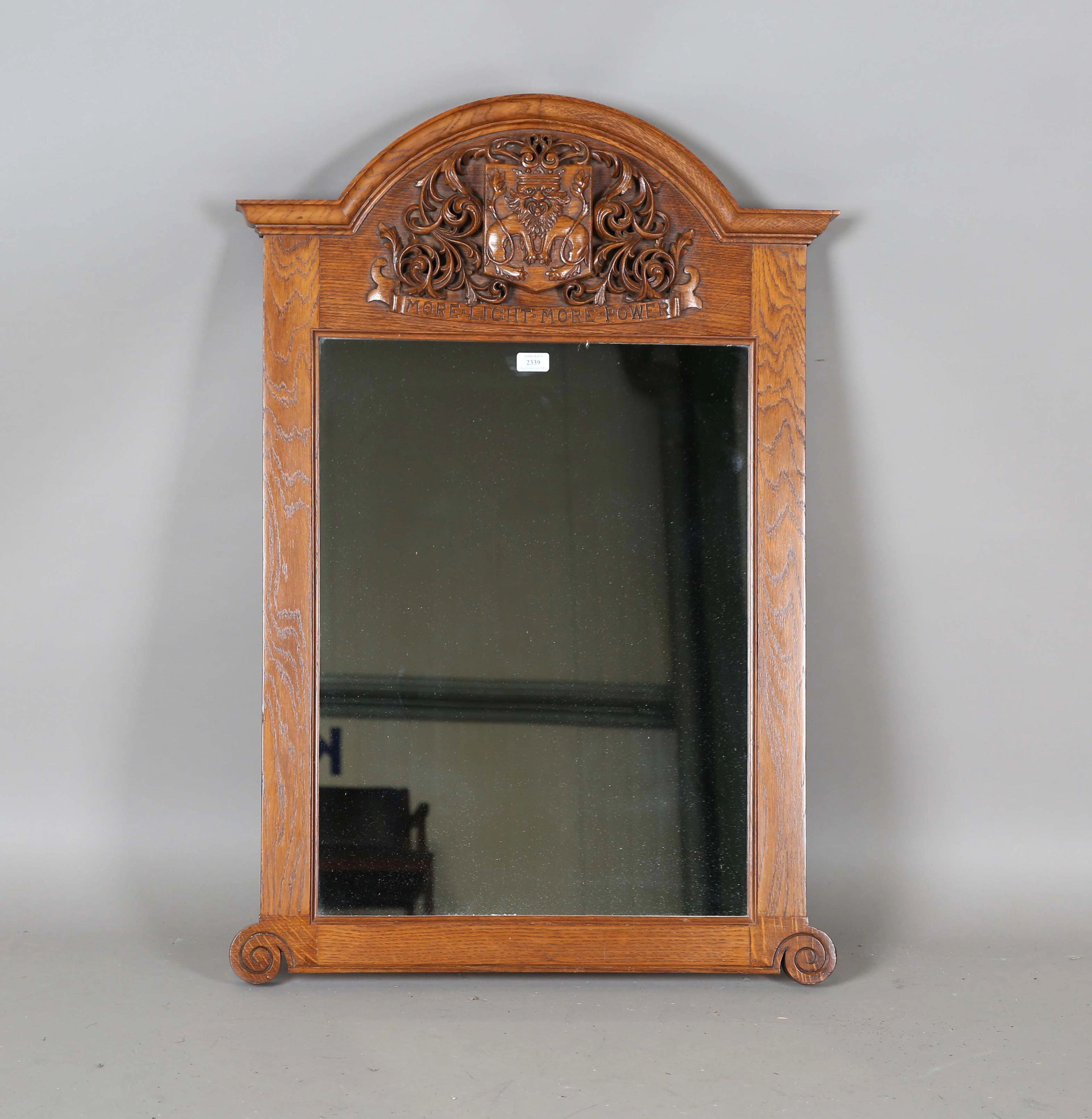 An early 20th century Arts and Crafts oak framed mirror, the arched